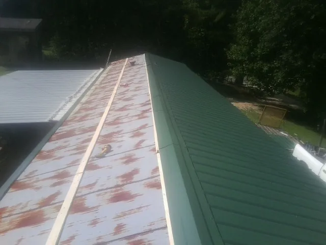 Old rusted panels beside newly installed green metal roofing — Wind Damage Roof Repair by Roofing Brothers in Everson