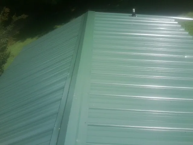 New green metal panels meeting at the ridge of a roof — Flat Roof Repair work by our crew in Everson