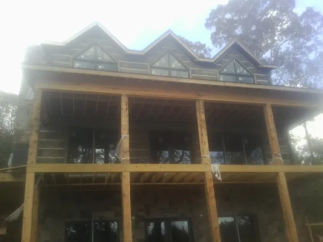 Dormers and porch framing on a large log home under construction — Roof Coating work by our crew in Everson