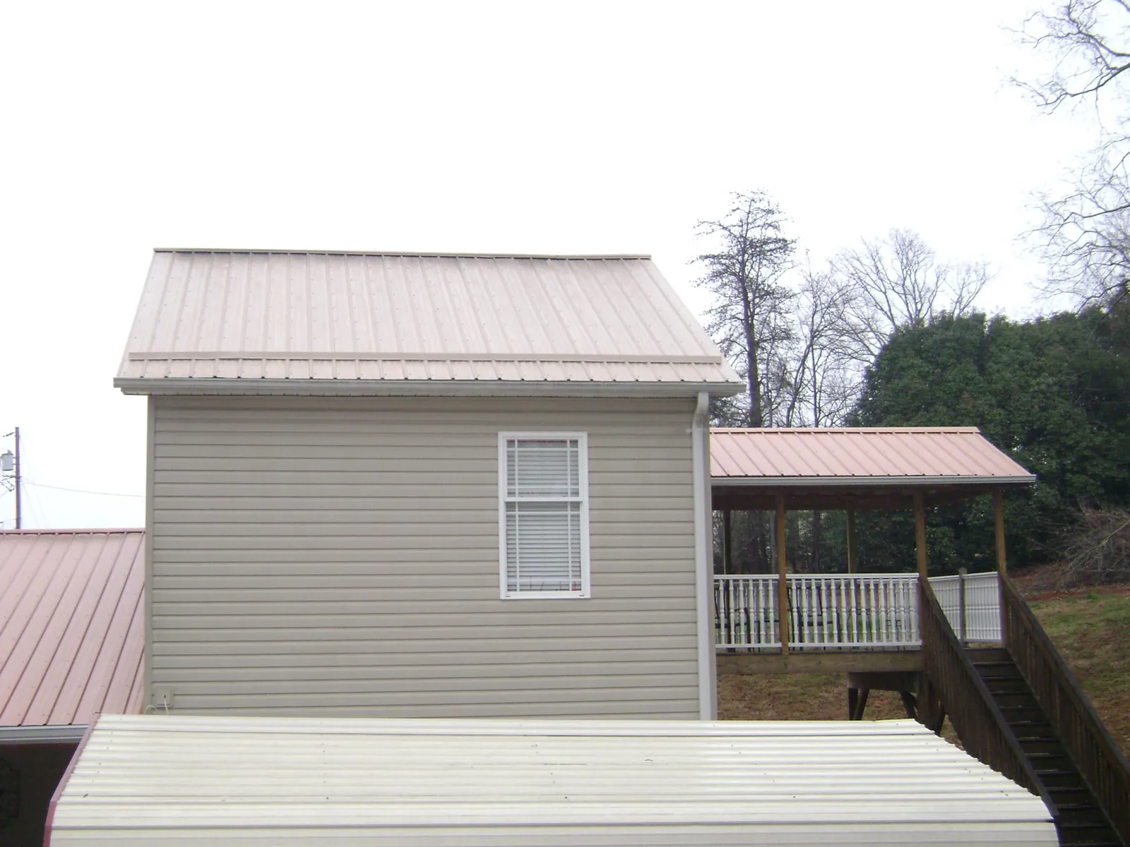 Tan metal roofs on a two story addition and attached porch, from a Roof Replacement job in Everson